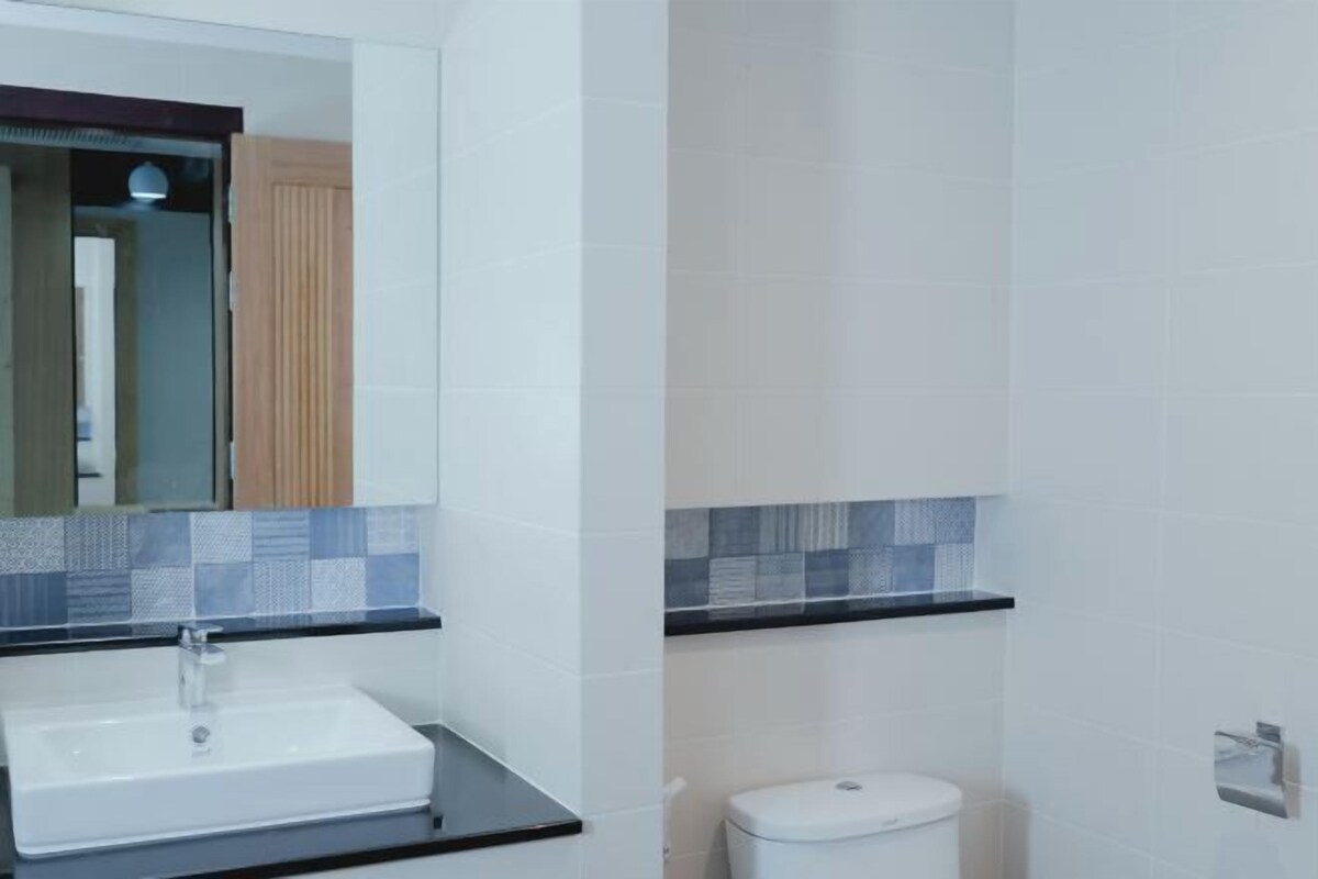 Un baño con un lavabo blanco, un espejo y un inodoro.