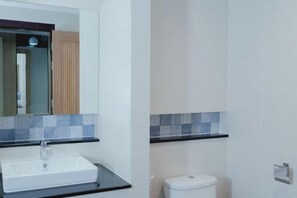 Un baño con un lavabo blanco, un espejo y un inodoro.