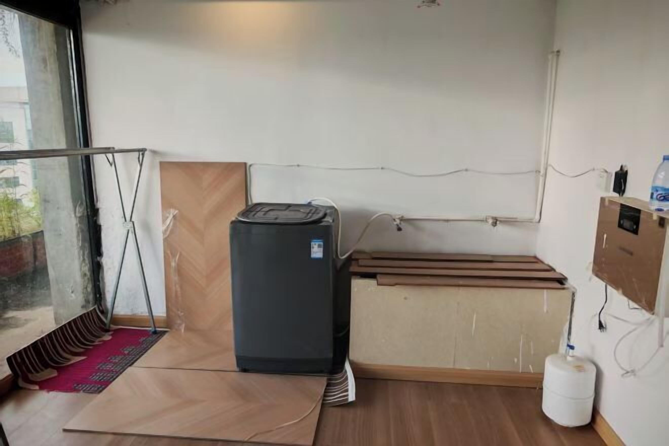Una habitación con distribución funcional, que incluye una pequeña kitchenette con refrigerador, un armario de madera y dispensador de agua.