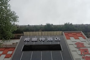 A hotel with a sign that reads '希雅特酒店' and a partial sign with red characters. - Xiyate Hotel (Xiangxiang)