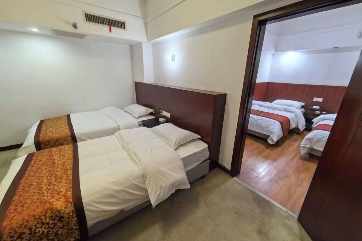 A hotel room with two beds, a wooden headboard, and a carpeted floor.