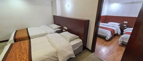 Habitación de hotel con dos camas, cabecero de madera y piso cubierto de alfombra.