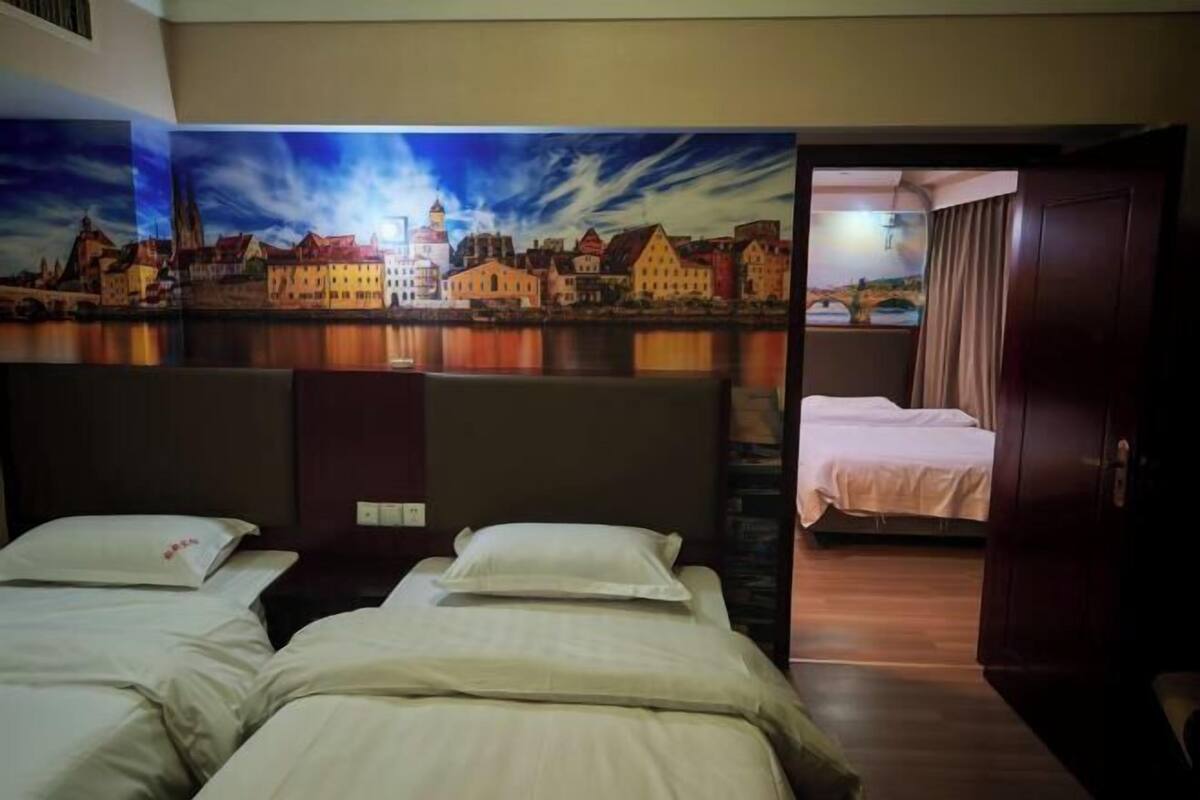 A hotel room with two beds, a cityscape mural, and a wooden floor.