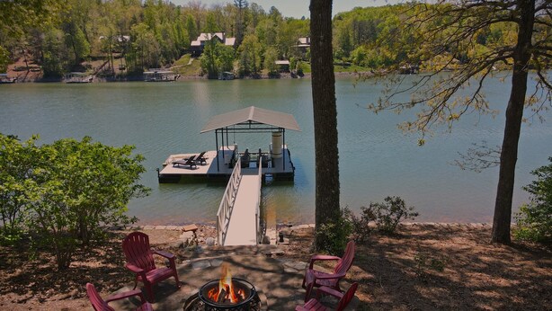 Une terrasse au bord du lac, avec un foyer, des sièges d’extérieur et une jetée qui s’avance dans l’eau.
