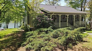 Une maison dotée d’un porche, entourée d’une végétation dense et d’arbres.