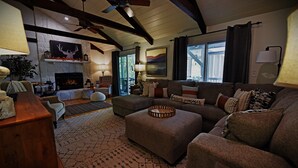 Un salon chaleureux avec une cheminée, des sièges confortables et un ventilateur de plafond.