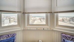 Een kamer met drie ramen met uitzicht op een straat en een wateroppervlak.