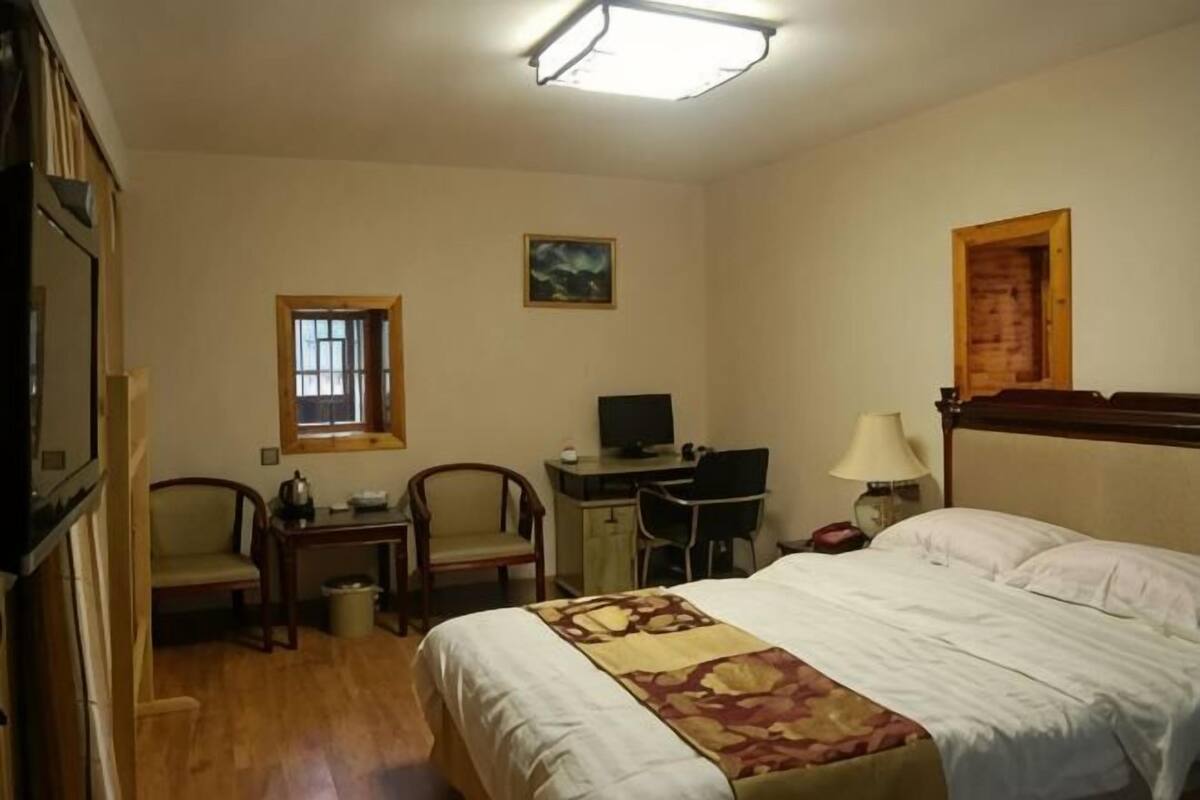Habitació d'hotel amb llit, escriptori, cadires, televisió i finestra.
