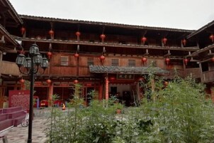 Un patio tradicional con edificios de madera, faroles rojos y una lámpara de calle.