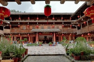 Un patio tradicional con balcones de madera, plantas en macetas y faroles colgantes.