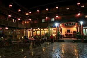Un patio tradicional con suelo de baldosas, muebles de madera y faroles colgantes.