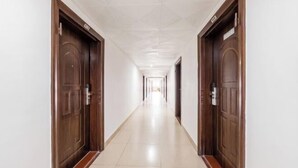 A long, narrow hallway with wooden doors on either side, leading to a bright room at the end. - 365 Business Stays Express Hotel (Zhangzhou)