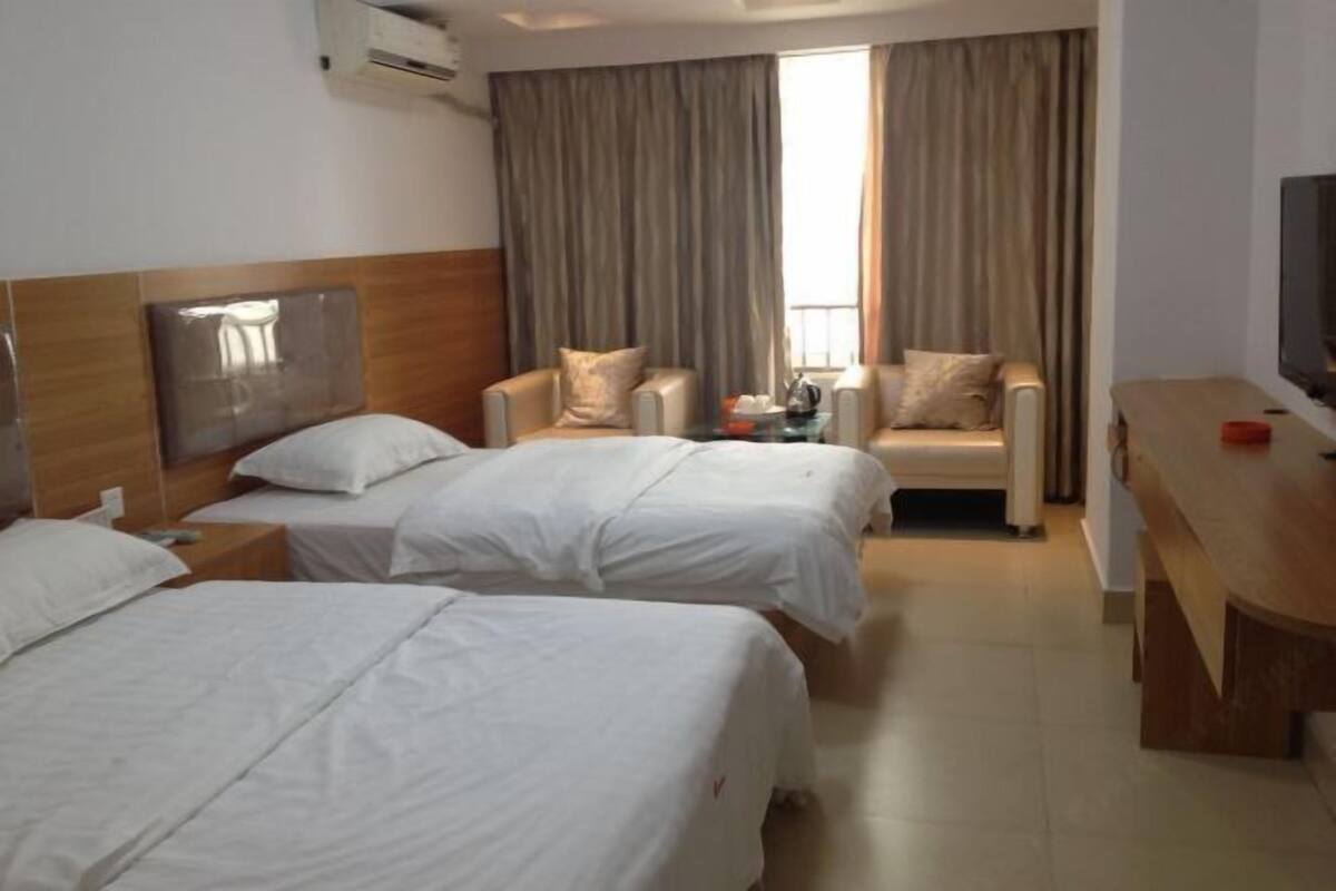 Habitación de hotel con dos camas, un sofá, un televisor y una ventana con cortinas.