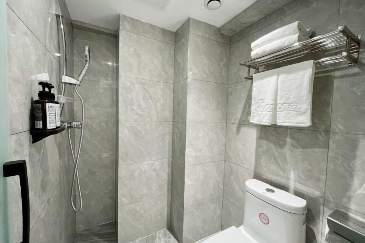 Une salle de bain moderne équipée d’une douche, de toilettes et d’un porte-serviettes.