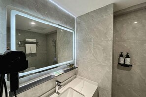 Une salle de bain moderne avec un grand miroir, un lavabo et un espace douche.