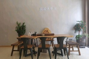 Un comedor con una mesa de madera, sillas negras y plantas en macetas.