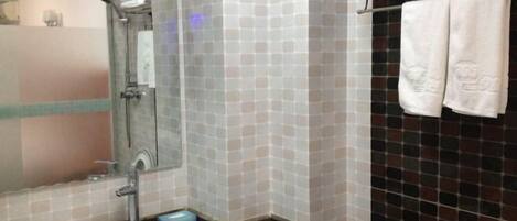 Un baño con lavamanos, espejo, ducha e inodoro.