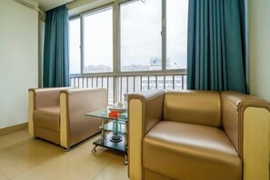 Une pièce avec deux canapés de couleur beige, une table basse en verre et une vue dégagée grâce à de grandes fenêtres.