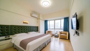 A hotel room with a large bed, a television, a desk with a chair, and a balcony with a view of the city. - 365 Business Stays Express Hotel (Zhangzhou)