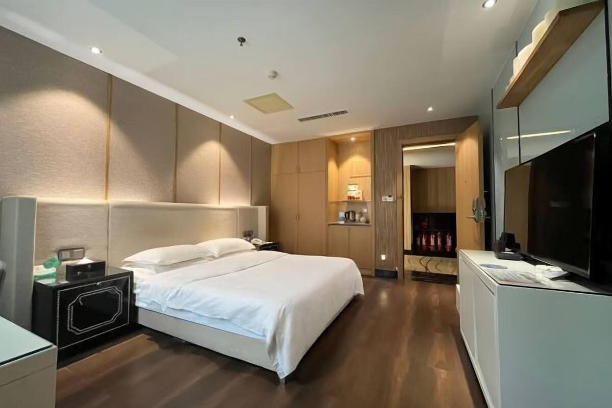 Une chambre d’hôtel moderne avec un grand lit, une table de chevet, une télévision et une armoire.