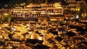 A traditional Chinese village with tiered buildings and illuminated windows.