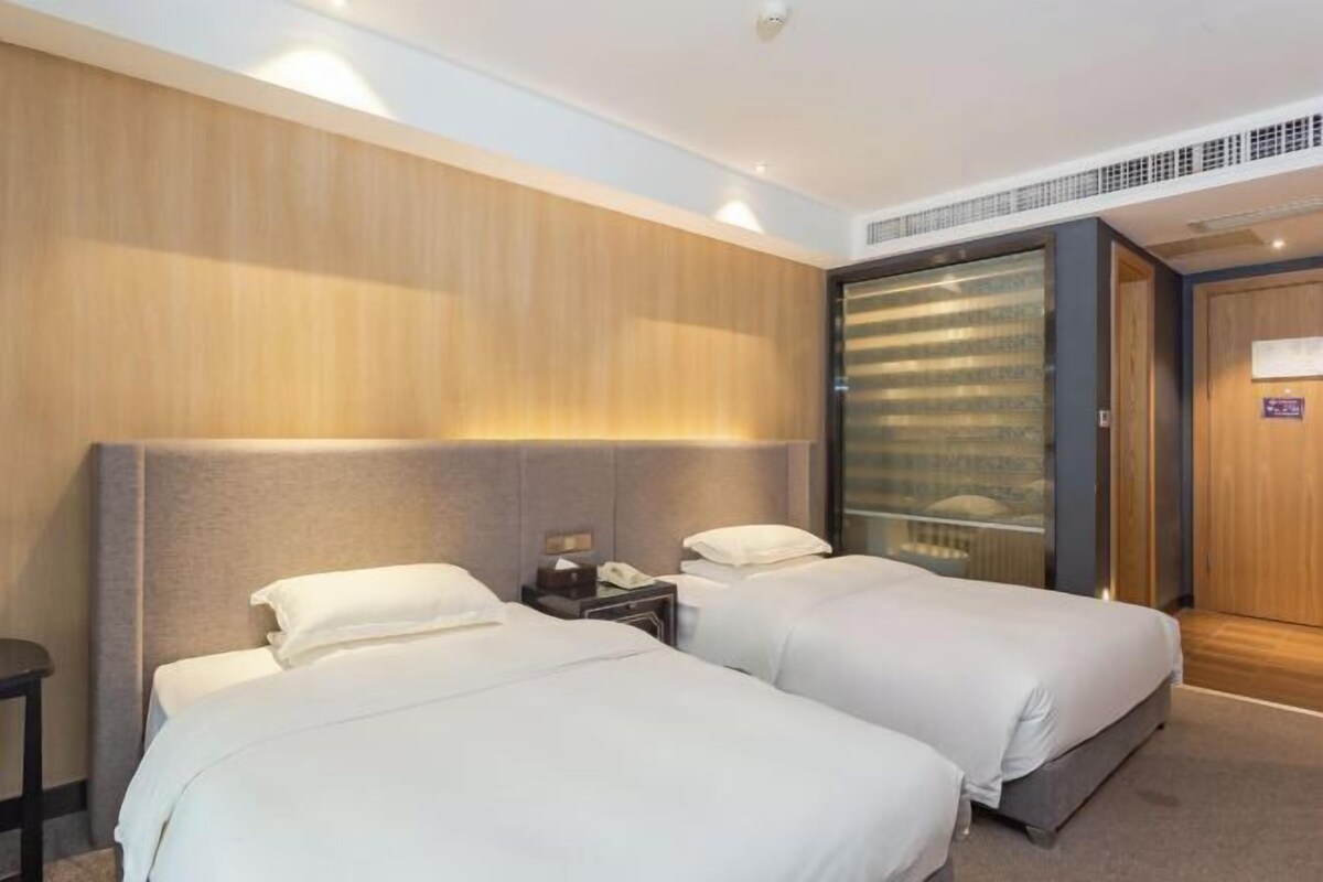 Ein Hotelzimmer mit zwei Betten, einem Nachttisch mit Telefon und einer Schiebetür zu einem Badezimmer.