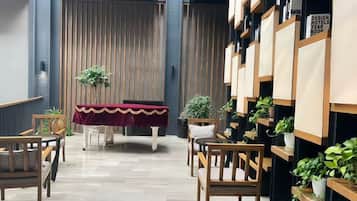 A hotel lobby with a reception desk, seating area, and a wall with framed pictures.
