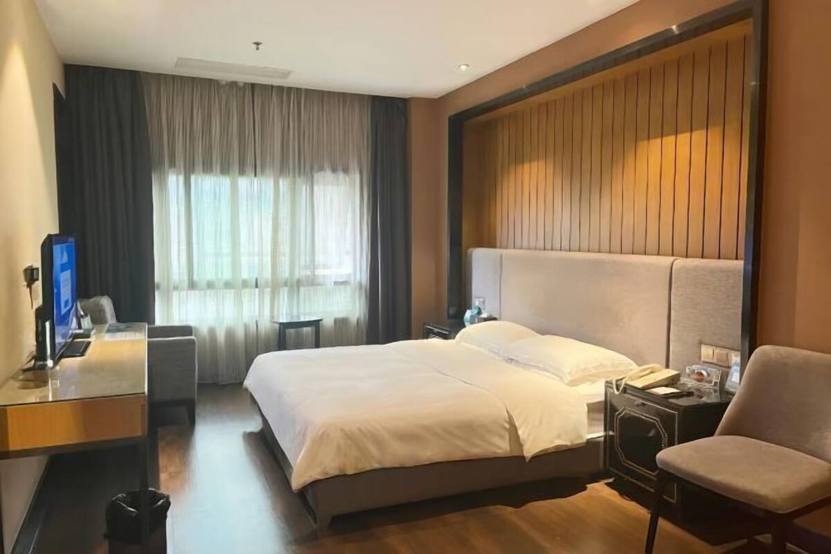 Une chambre d’hôtel avec un grand lit, un bureau, une chaise et un téléviseur.