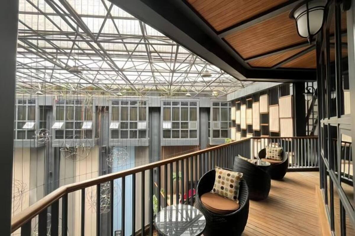 Un balcon doté d’un toit en verre, d’un plancher en bois et d’espaces aménagés pour s’asseoir.