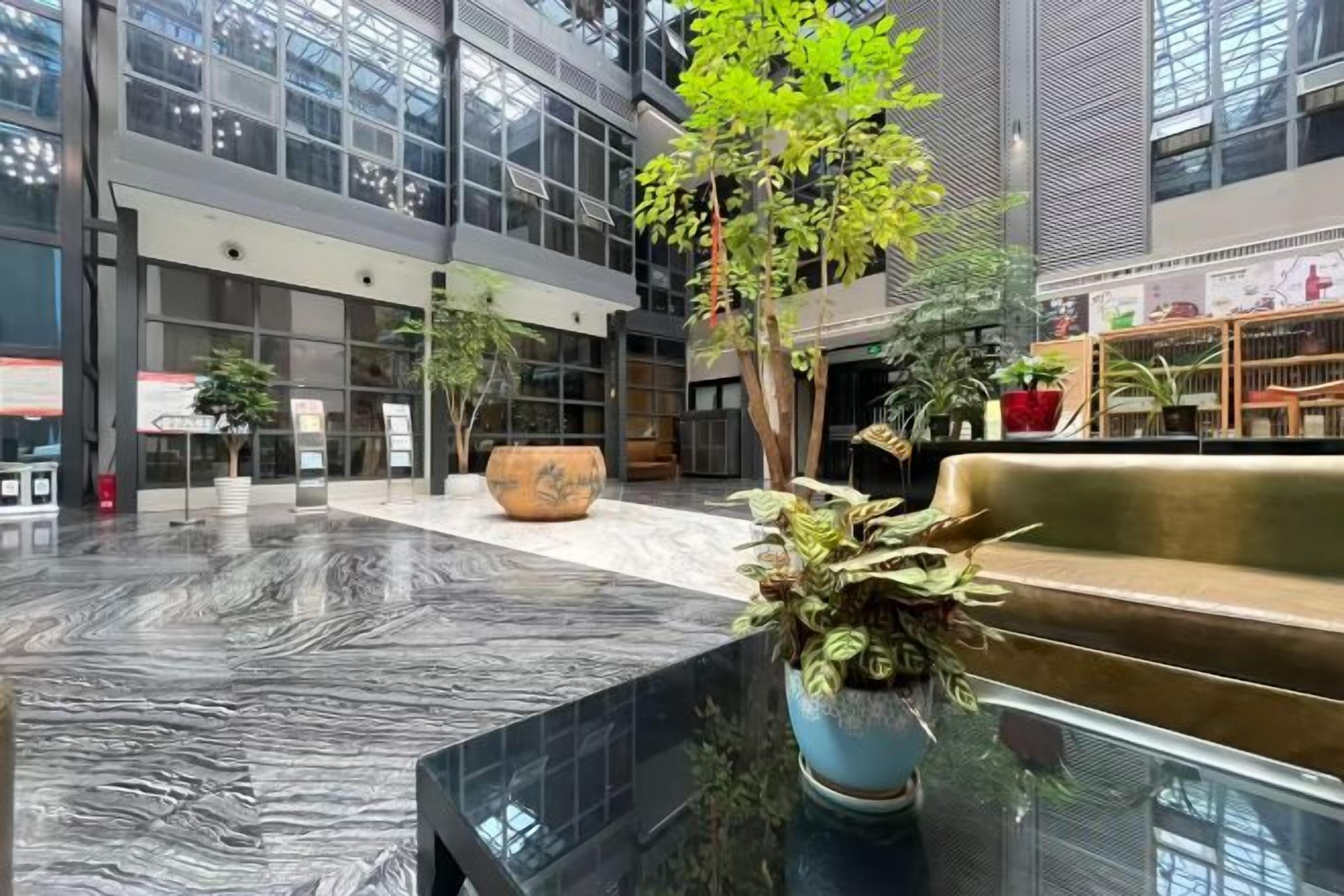 A spacious indoor area with a marble floor, seating areas, and potted plants.