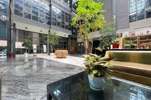 A spacious indoor area with a marble floor, seating areas, and potted plants.