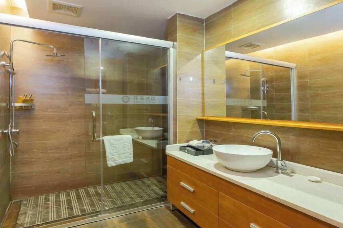 Ein modernes Badezimmer mit einer gläsernen Duschkabine, einem großen Spiegel und einem Holzwaschtisch mit weißem Waschbecken.