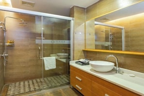 A modern bathroom with a glass-enclosed shower, a large mirror, and a wooden vanity with a white sink.