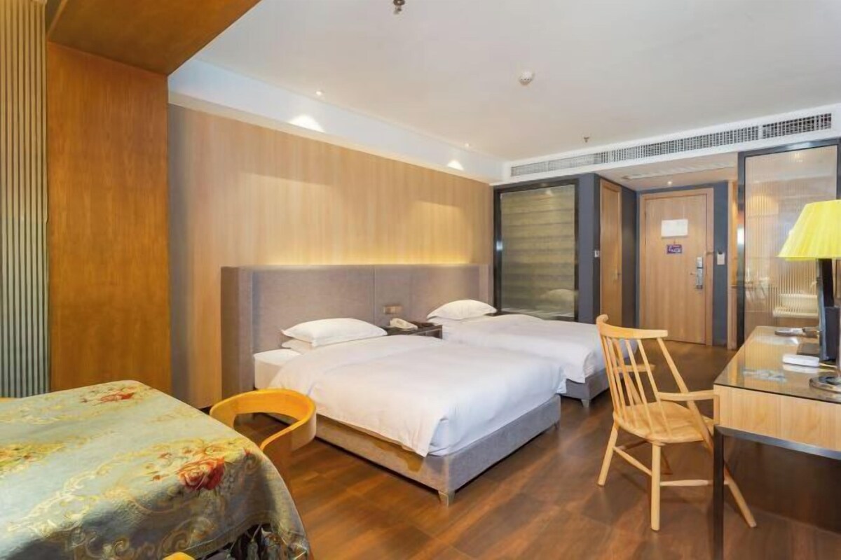 Ein Hotelzimmer mit zwei Betten, einem Schreibtisch, einem Stuhl und einem kleinen Tisch.