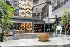 A multi-level atrium with a central seating area, a reception desk, and a variety of plants. - Zunyi Wanshou Garden Hotel (Zunyi)