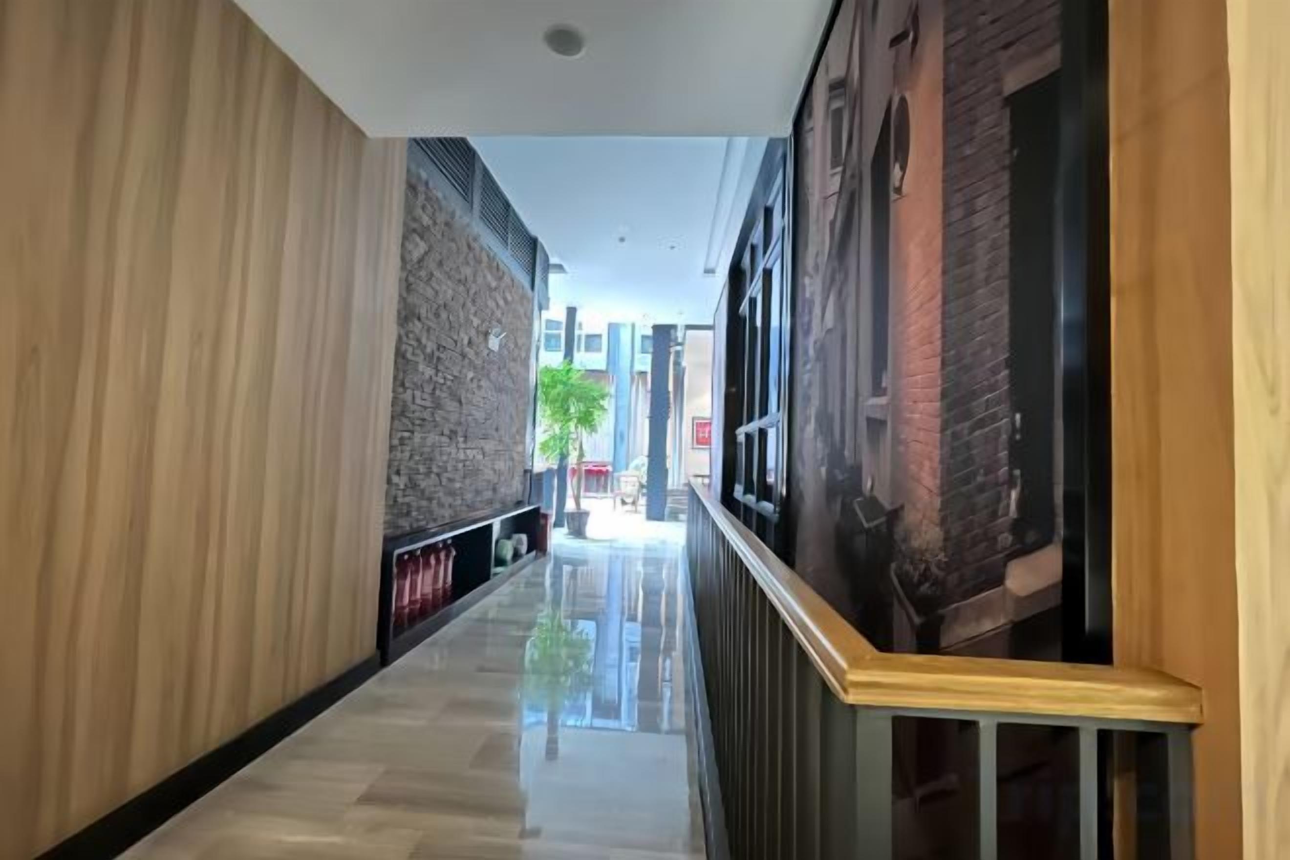 A corridor with a polished floor, wooden paneling on one side, and a metal railing on the other.