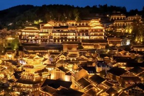 Uma aldeia tradicional chinesa à noite, com edifícios iluminados e uma disposição densa de construções.