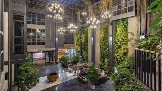A spacious indoor area with a high ceiling, large windows, and hanging spherical light fixtures.