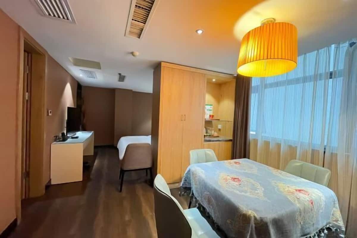 Une chambre d’hôtel avec un lit, un bureau, une chaise, une armoire et une fenêtre avec des rideaux.