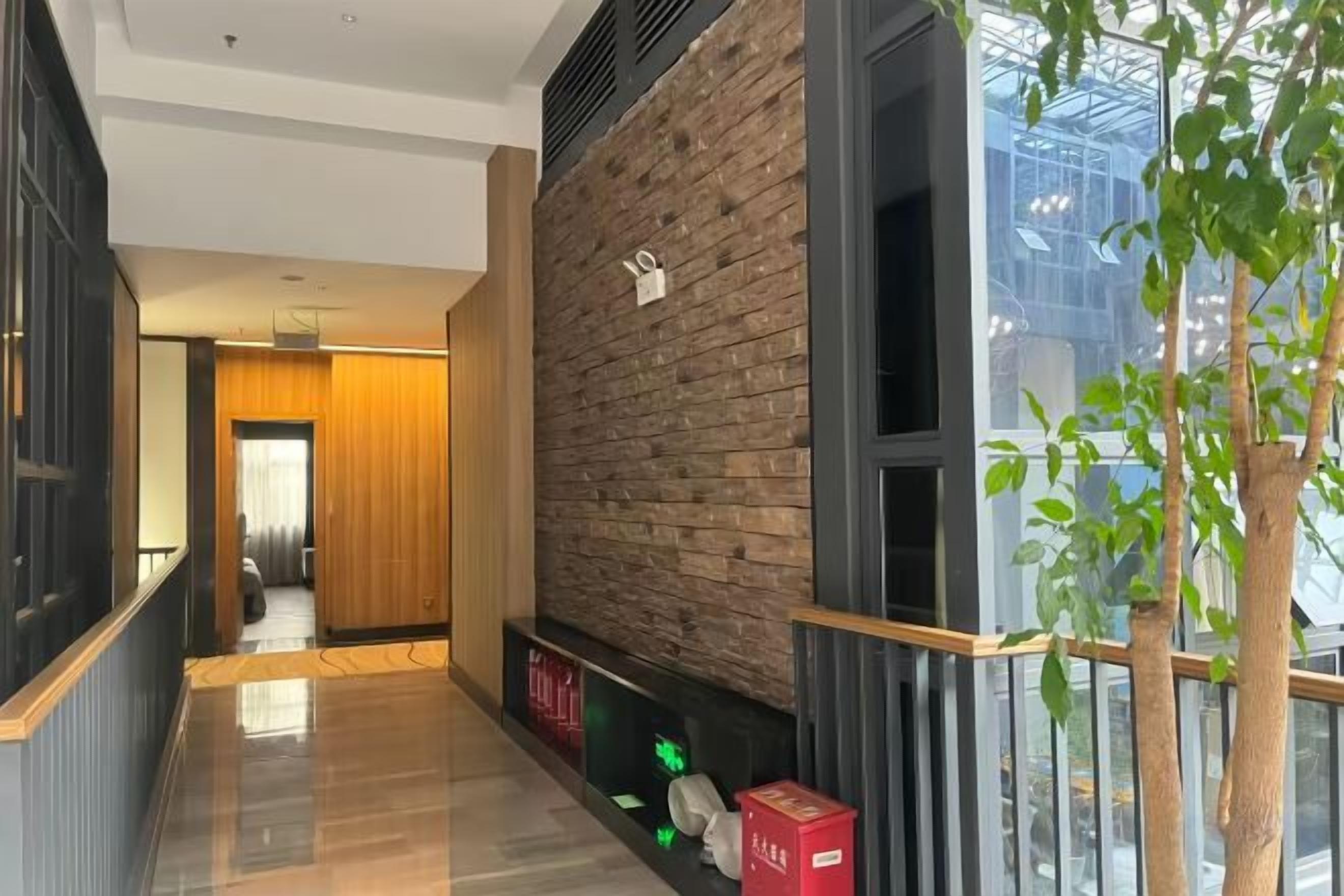 A corridor with a wooden wall, a glass window, and a plant.