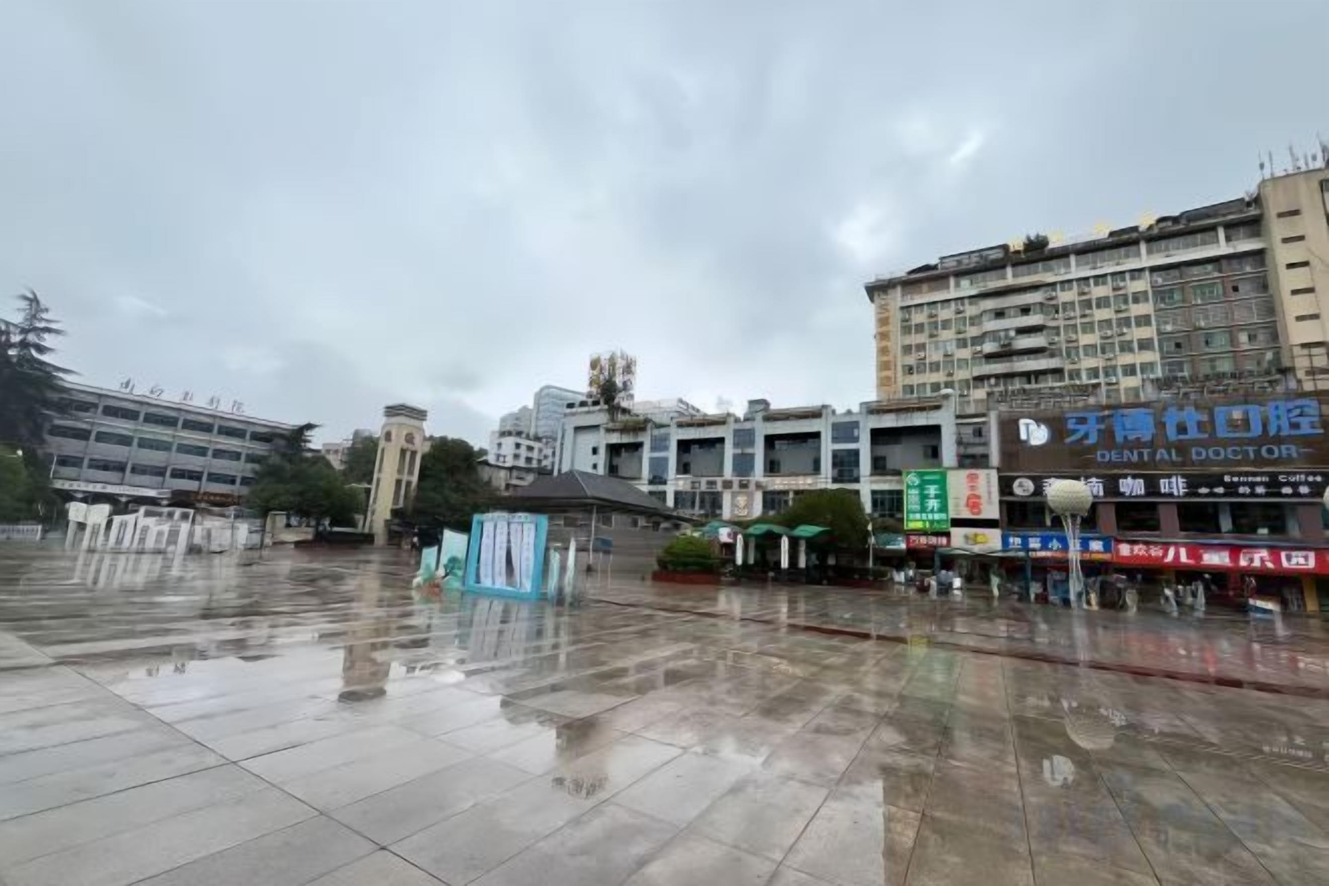 A wet plaza with a building featuring a dental clinic sign.