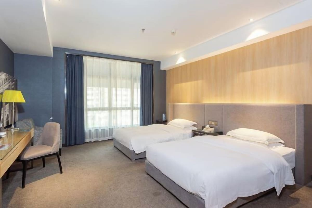 Ein Hotelzimmer mit zwei Betten, einem Schreibtisch und einem Stuhl.