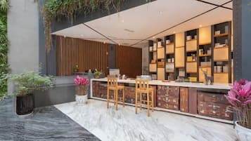 A modern reception area with a marble floor, wooden chairs, a counter with storage boxes, and a bookshelf.