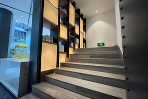 Una escalera con peldaños de madera que conduce a un rellano con un letrero de salida verde.