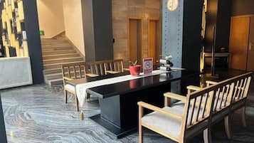 Un vestíbulo de hotel con mostrador de recepción, zona de estar y una escalera.
