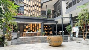 A modern hotel lobby with a central seating area, a reception desk, and multiple floors with balconies.
