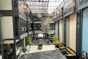 Un amplio atrio con techo alto, ventanas grandes y modernas lámparas.