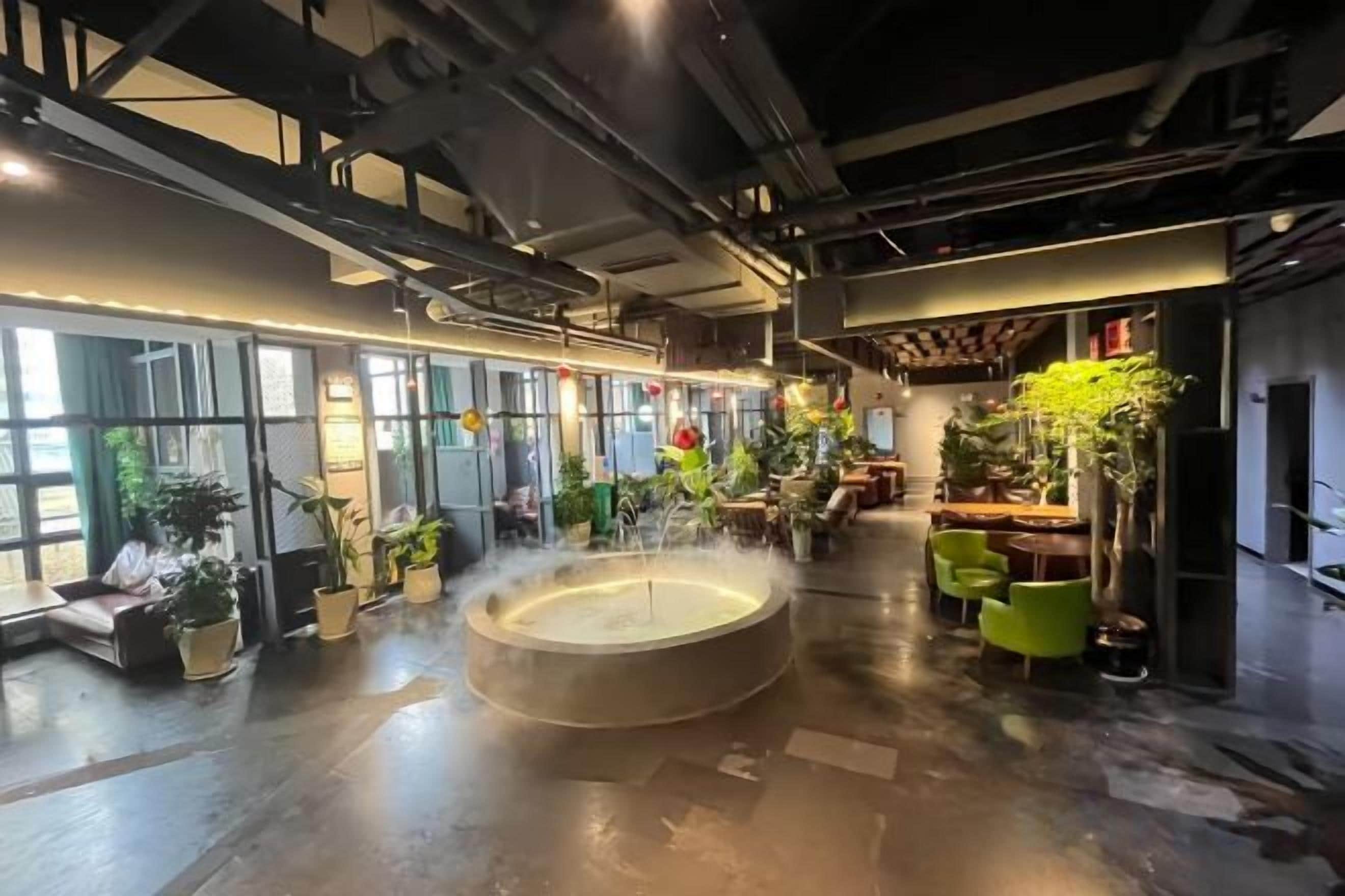 Amplio espacio interior con una fuente central, arreglos de asientos y plantas en macetas.