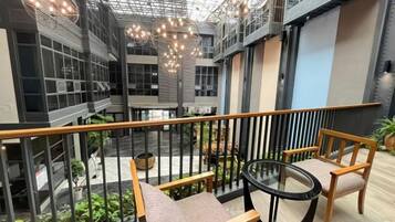 An indoor atrium with a glass ceiling, wooden seating, and potted plants.
