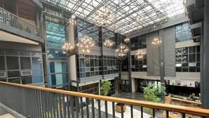 A modern interior with a glass ceiling, multiple floors, and a central atrium with seating and plants.